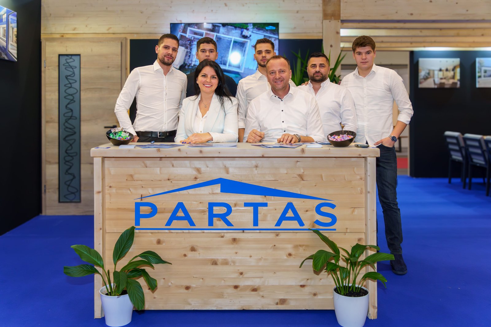 The PARTAS team standing behind their branded wooden stand at a trade fair