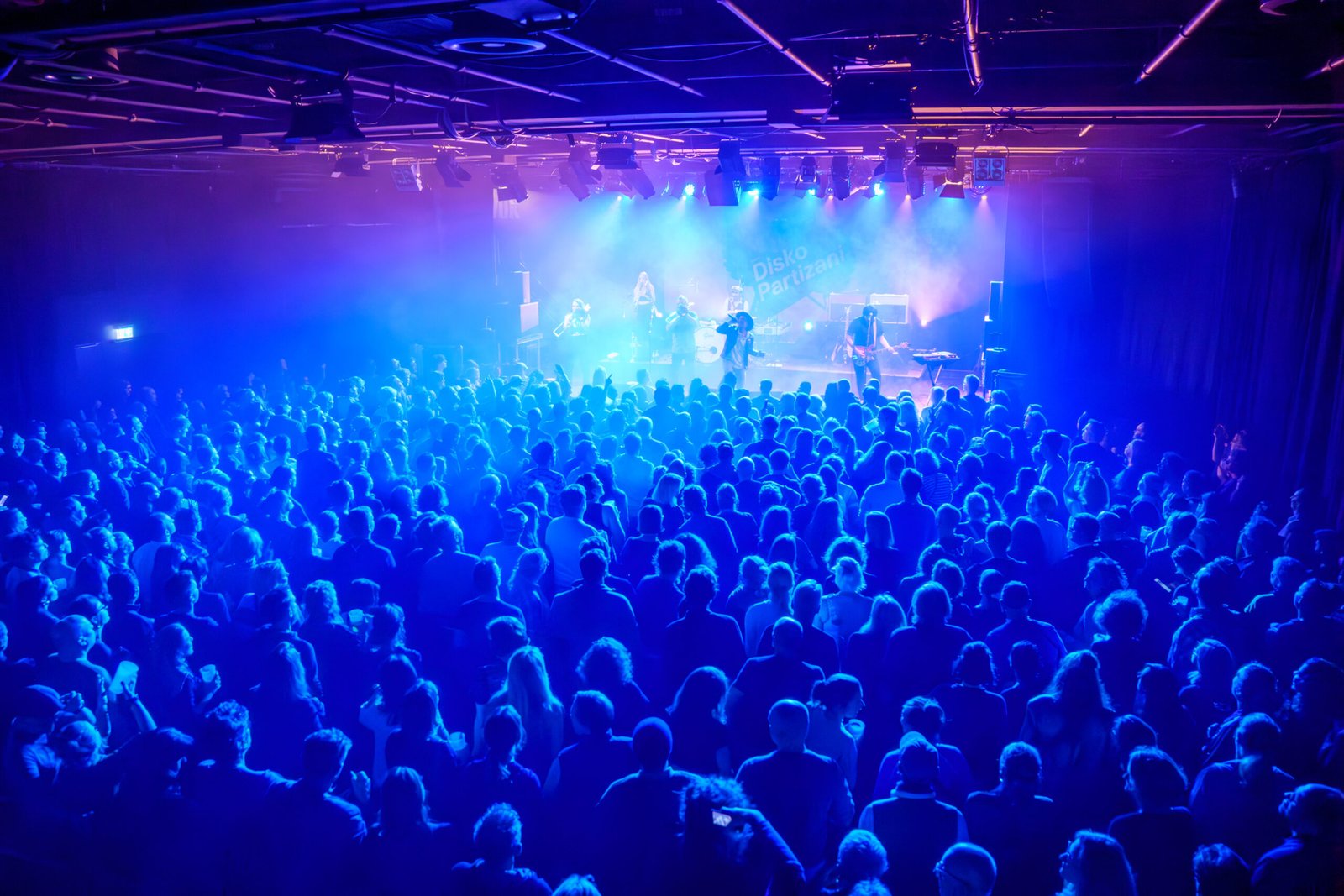 Packed concert hall bathed in blue stage light