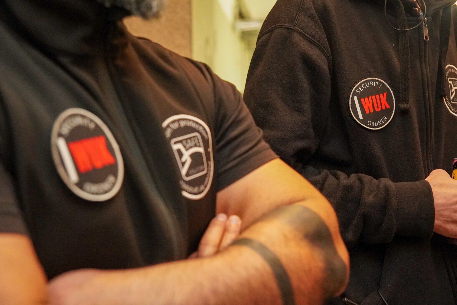 Close-up of Safe Solutions staff with crossed arms showing WUK and company patches