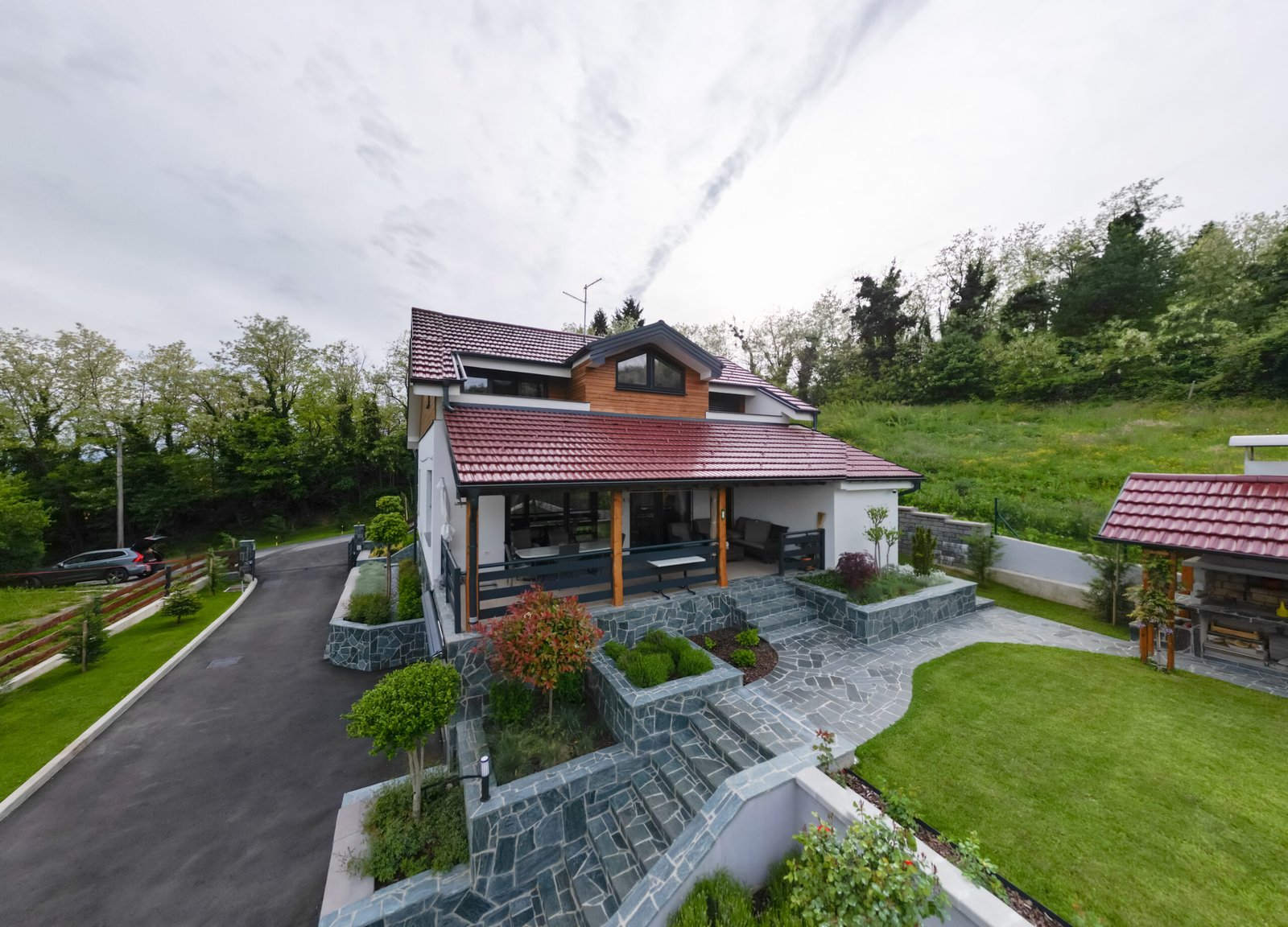 Aerial view of a finished PARTAS house with red roof, driveway and surrounding greenery