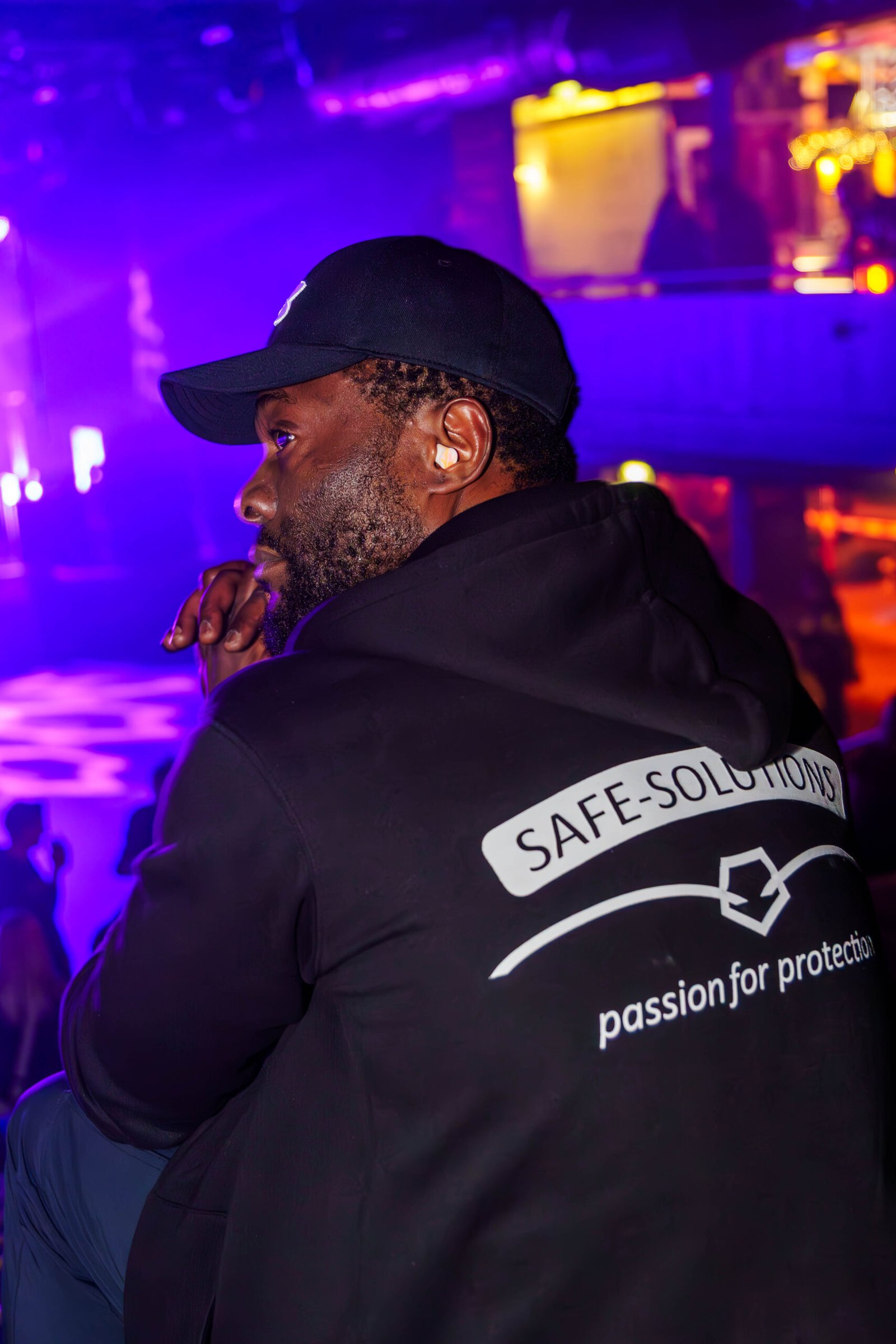 Safe Solutions guard speaking into a radio under purple club lighting