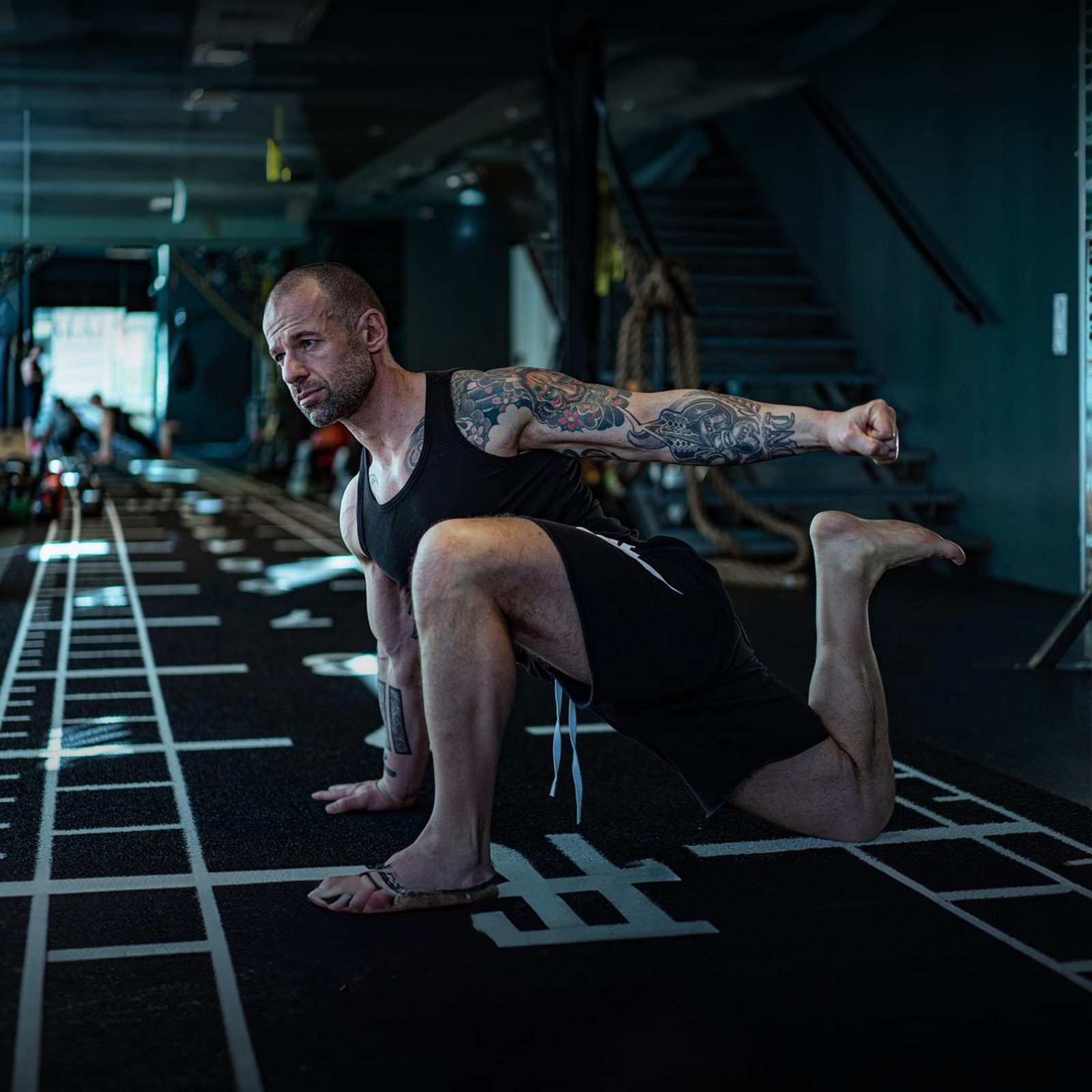 DNT coach in a low lateral lunge on the gym floor